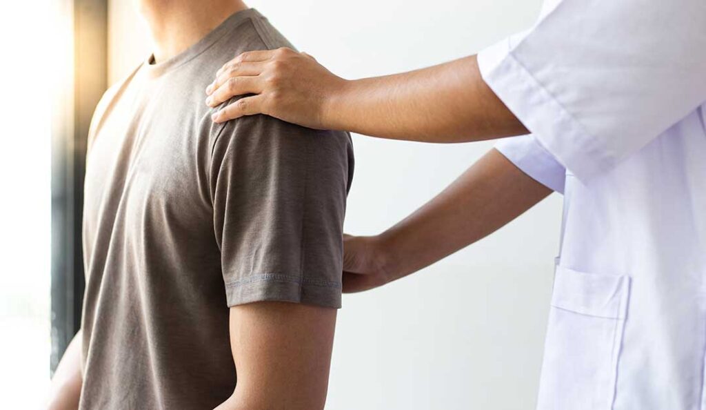 A chiropractor demonstrating a spine diagram to a patient in an exam room.