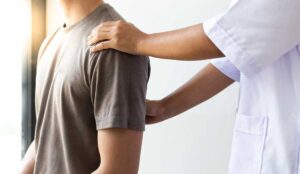 A chiropractor demonstrating a spine diagram to a patient in an exam room.